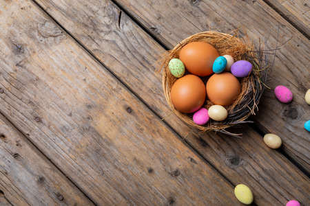 Close-up of easter eggs and colorful candies in nest on wooden table. unaltered, cultures, festival, craft, sweet food, candy, decoration and celebration concept.の写真素材