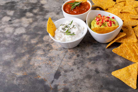 Close-up of nacho chips with various dipping sauces served on table. unaltered, unhealthy food,...