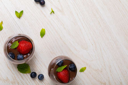 Strawberries, blueberries and mint leaves with chocolate dessert in bowls on table with empty space. unaltered, copy space, dessert, sweet food, berry fruit, herb and chocolate indulgence.の写真素材