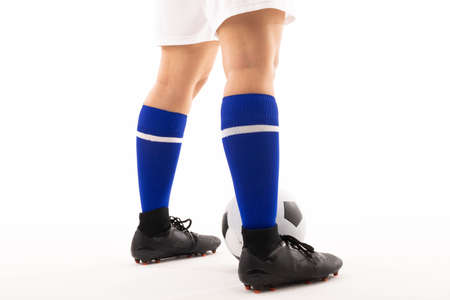 Low section of biracial young female player with soccer ball standing against white background. unaltered, sport, soccer shoe, sock, copy space, athlete and women's soccer.の写真素材