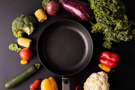 Overhead view of empty frying pan amidst various vegetables on black background. unaltered, healthy food, vegetable, raw food, variation and organic concept.の写真素材