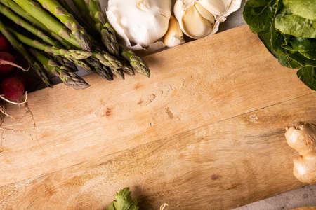 High angle view of wooden cutting board by vegetables and spices on table. unaltered, copy space, healthy food, vegetable, raw food, variation and organic concept.の写真素材