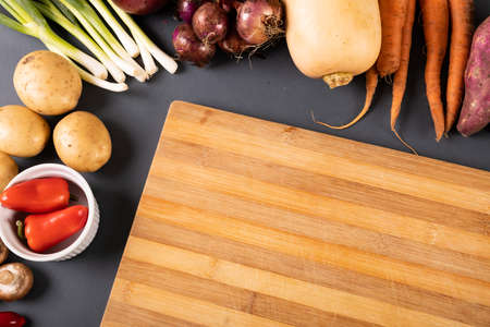 High angle view of cutting board by various vegetables and spices on gray background. unaltered, variation, healthy food, vegetable, raw food and organic concept.の写真素材