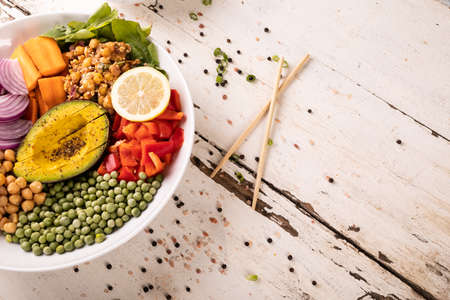 High angle view of fresh meal in bowl by scattered peppercorn on white wooden table. unaltered,...