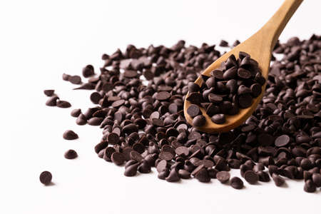 Close-up of wooden spoon with chocolate chips against white background. unaltered, sweet food and...