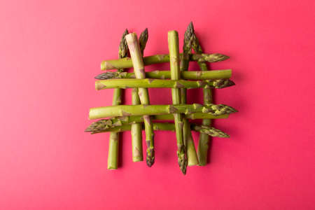 Overhead view of fresh green asparagus stacked on pink background amidst copy space. unaltered, food, healthy eating and organic concept.の写真素材