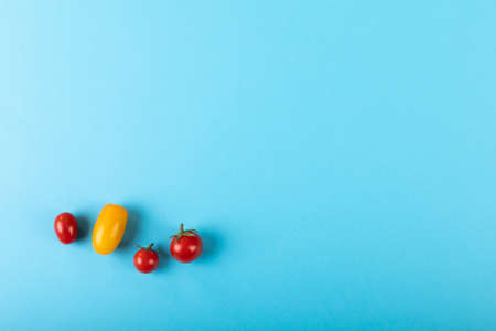 Directly above view of copy space with fresh yellow and red tomatoes on blue background. unaltered, organic food and healthy eating concept.の写真素材