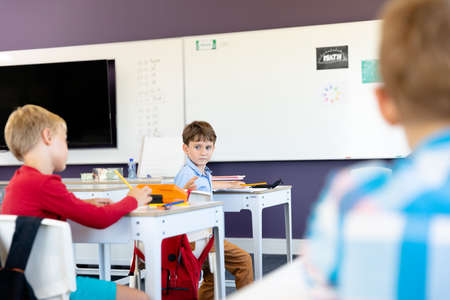 Caucasian elementary schoolboys sitting at desk in classroom. unaltered, childhood, education and back to school concept.の写真素材