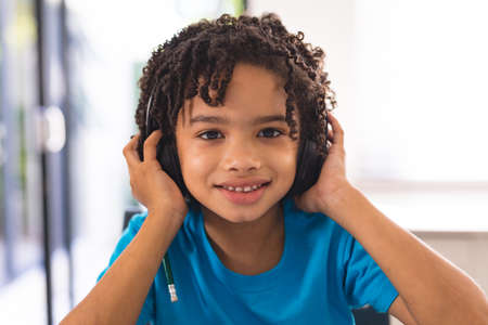 Portrait of smiling hispanic cute boy wearing headphones at home. unaltered, childhood and technology concept.の写真素材
