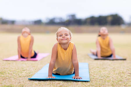 Multiracial elementary schoolgirls doing upward facing dog pose exercise on yoga mat. unaltered,...