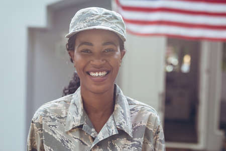 Portrait of smiling female mid adult african american soldier in uniform standing outside house. unaltered, pride, homecoming, military, armed forces and patriotism concept.の写真素材