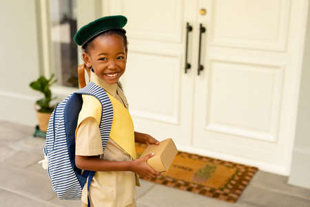 Smiling african american scout girl in uniform delivering package at home. unaltered, girl scout,...