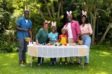 Happy african american multigenerational family in bunny ears with easter eggs in backyard. unaltered, lifestyle, easter day, art, celebration, family, cultures and holiday concept.の写真素材