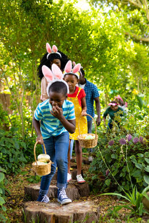 African american multi-generational family with baskets hiding easter eggs in backyard. unaltered, lifestyle, easter day, celebration, childhood, cultures and holiday concept.の写真素材