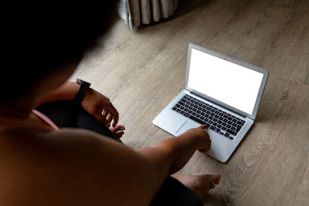 High angle view of african american mid adult woman using laptop while exercising at home. unaltered, copy space, wireless technology, fitness and active lifestyle concept,の写真素材