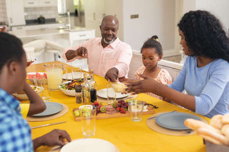 Happy african american multi-generational family having lunch together at home on thanksgiving day. unaltered, family, food, togetherness, cultures and holiday concept.の写真素材