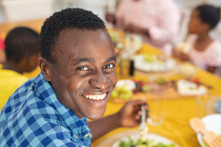 Portrait of smiling african american mid adult man having lunch with family on thanksgiving day. unaltered, family, food, togetherness, cultures and holiday concept.の写真素材