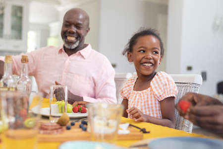 Happy african american girl having lunch with family at home on thanksgiving day. unaltered, family,...