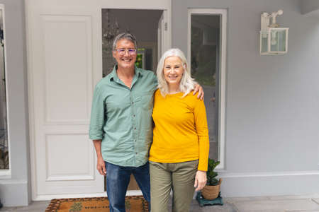 Portrait of happy caucasian senior couple at entrance of house. unaltered, lifestyle, togetherness,...