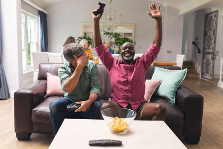 Multiracial senior male friends enjoying video game at home. unaltered, lifestyle, enjoyment, fun, friendship and togetherness.の写真素材