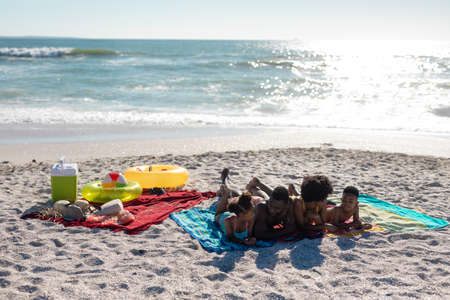 Happy african american family lying together at beach enjoying summer holiday together. unaltered, family, lifestyle, togetherness, enjoyment and holiday concept.の写真素材