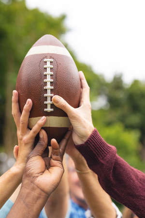 Cropped image of multiracial senior male and female friends holding rugby ball, copy space. unaltered, lifestyle, friendship, leisure, sport and active seniors.の写真素材
