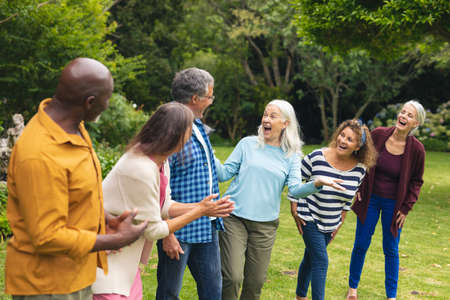 Happy multiracial senior male and female friends having fun in backyard. unaltered, lifestyle,...