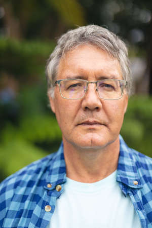 Portrait of confident caucasian senior man with eyeglasses in backyard on weekend. unaltered,...