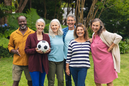 Portrait of smiling multiracial active senior male and female friends with soccer ball in backyard. unaltered, lifestyle, friendship, leisure, sport and active seniors.の写真素材
