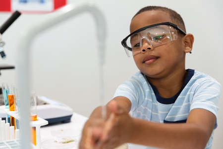African american elementary boy washing hands during chemistry laboratory class. unaltered,...