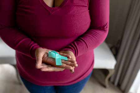 Midsection of african american mid adult woman showing prostate cancer awareness blue ribbon....