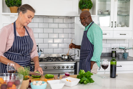 Senior multiracial couple preparing food together in kitchen at home. unaltered, lifestyle,...