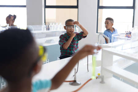 African american elementary schoolboys performing scientific experiment during chemistry class....