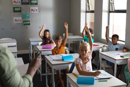 Cropped hand of african american young male teacher teaching multiracial students with hand raised....