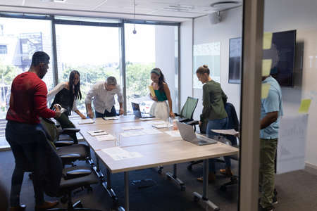 Multiracial male and female business colleagues attending meeting in boardroom at modern workplace....