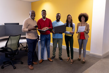 Full length portrait of happy multiracial male and female advisors in modern workplace. unaltered,...