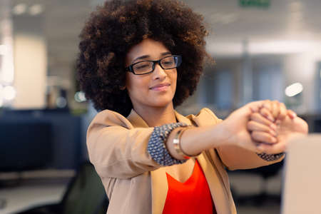 Beautiful young female african american advisor stretching arms at modern workplace. unaltered, business and modern office concept.の写真素材