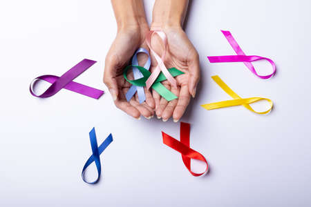 Hands of african american mid adult woman with colorful awareness ribbons on white background. copy space, medical, ribbon, awareness, support, healthcare and alertness concept.の写真素材
