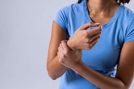 Midsection of african american mid adult woman with wrist pain against white background, copy space....