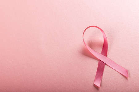 Close-up of breast cancer awareness pink ribbon isolated against pink background, copy space. breast, cancer, medical, ribbon, awareness, support, healthcare and alertness concept.の写真素材