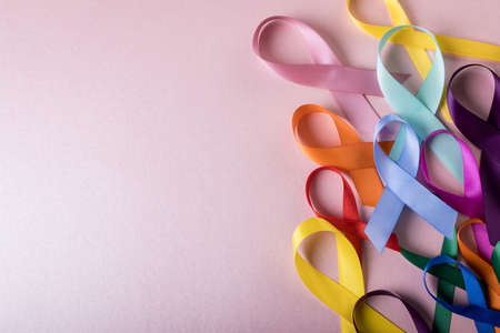 Directly above shot of various colorful awareness ribbons on pink background, copy space. medical, ribbon, awareness, support, disease, healthcare and alertness concept.の写真素材