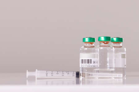 Close-up of syringe with vials on table against white background, copy space. vial, syringe, medical, vaccine, medicine, disease, needle, treatment and healthcare concept.の写真素材