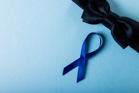 Directly above shot of blue prostate cancer awareness ribbon with black bowtie over blue background. copy space, prostate, cancer, medical, awareness, support, healthcare and alertness concept.の写真素材