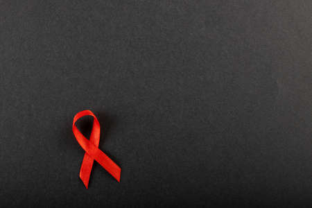 Directly above shot of red aids awareness ribbon isolated against black background, copy space. hiv, aids, red, medical, disease, ribbon, awareness, support, healthcare and alertness concept.の写真素材