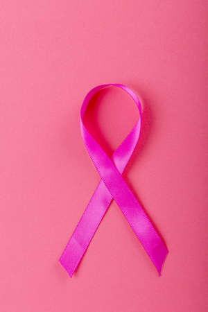 Overhead close-up of breast cancer awareness pink ribbon isolated over pink background. copy space. pink, breast, cancer, medical, ribbon, awareness, support, healthcare and alertness concept.の写真素材