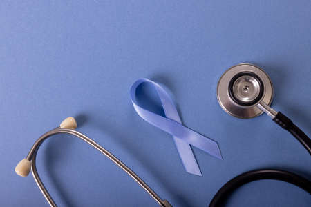 Directly above shot of blue stomach cancer awareness ribbon and stethoscope on blue background. medical, test, stomach, cancer, ribbon, awareness, support, healthcare and alertness concept.の写真素材