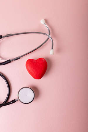 Directly above shot of stethoscope with red heart shape against pink background, copy space. heart, cardiac, medical, equipment, disease and healthcare concept.の写真素材