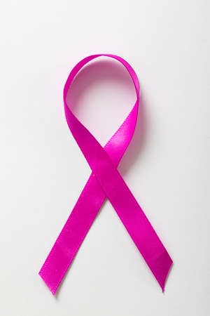 Overhead view of pink breast cancer awareness ribbon isolated on white background, copy space. pink,...