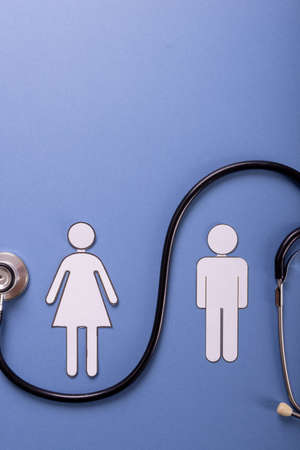 Directly above shot of paper couple with stethoscope against blue background, copy space. human representation, love, togetherness, sexual, medical, test and healthcare concept.の写真素材
