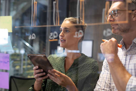 Confident caucasian colleagues brainstorming strategy together seen through meeting room glass wall....